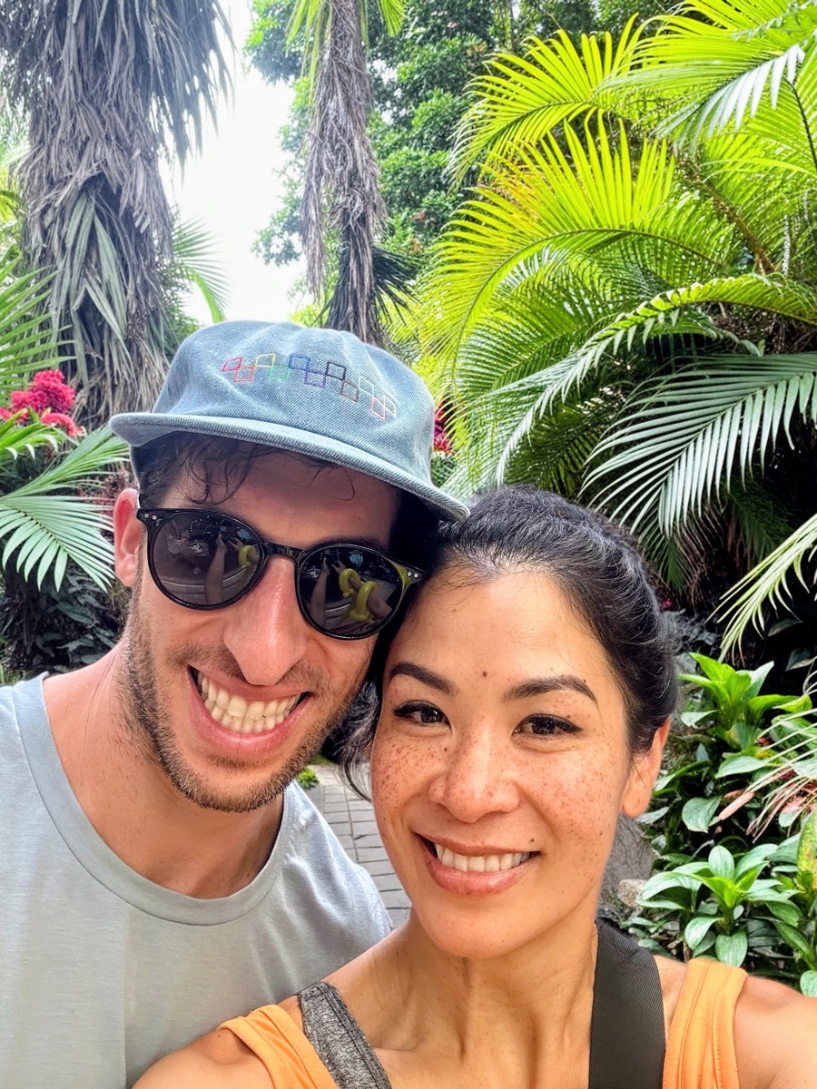 Lan and Clay smiling together beneath tropical palms